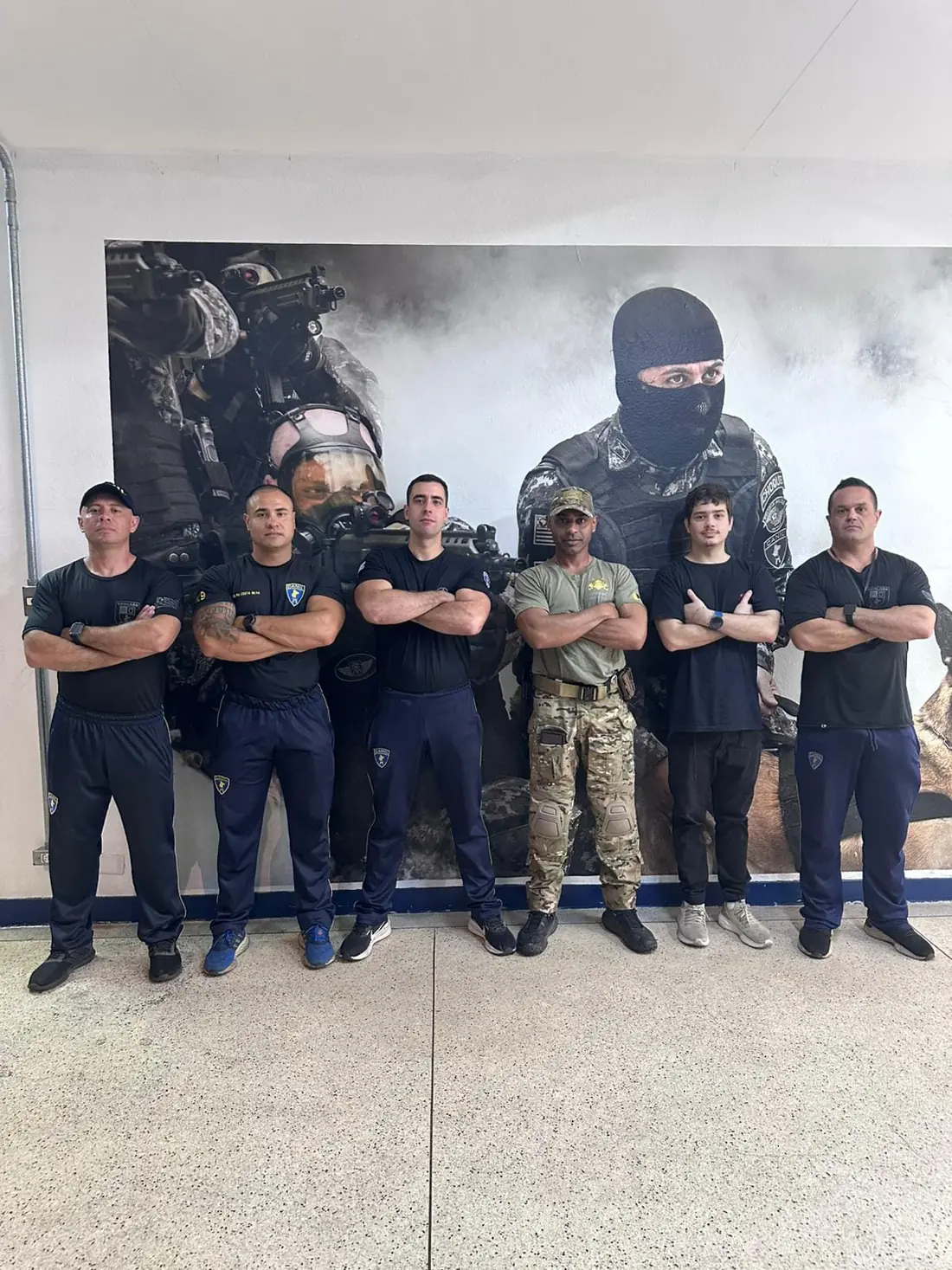 Jeremy standing with a group of working-dog handlers in front of a tactical K9 unit mural