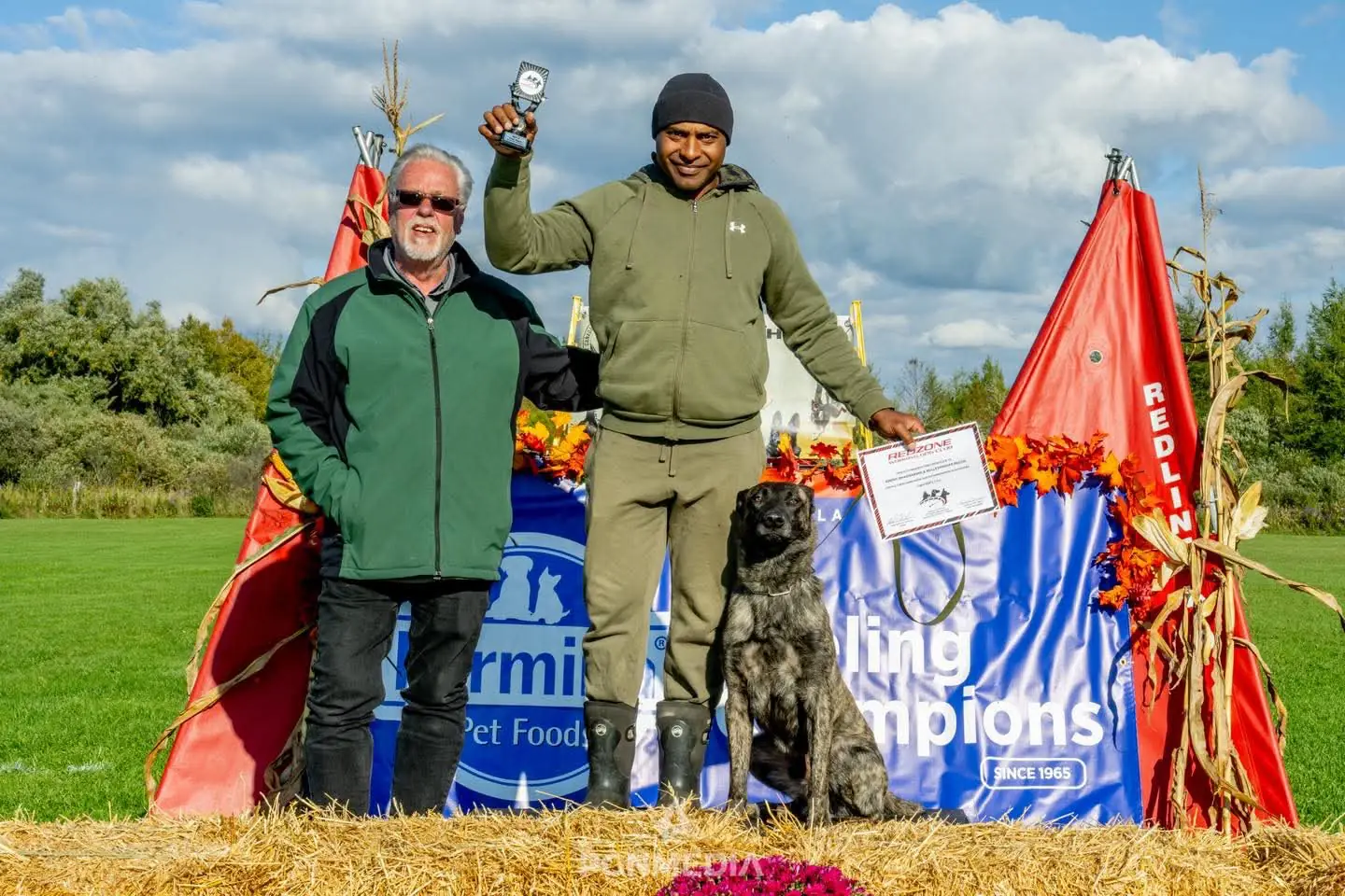 Jeremy holding a trophy and certificate beside his dog at a working-dog trial